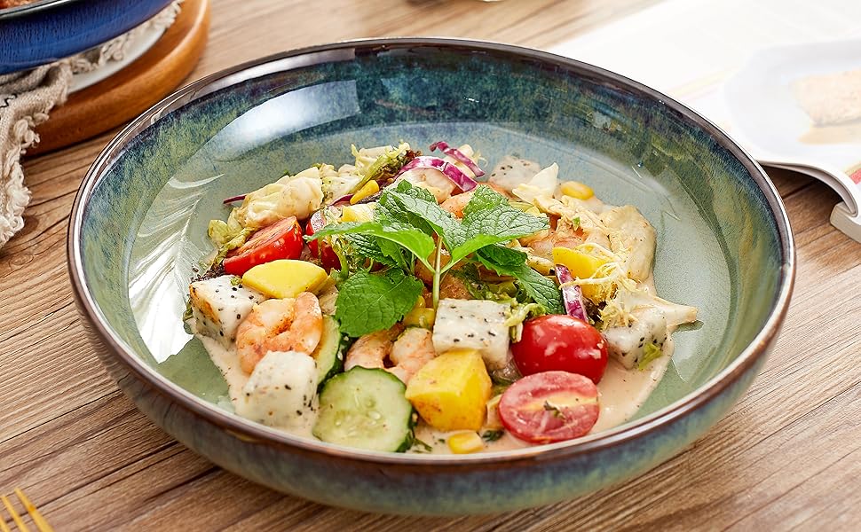 Fresh salad served in a blue-green ceramic bowl featuring colorful ingredients including tomatoes, cucumbers, and herbs, with seasonings visible in background.