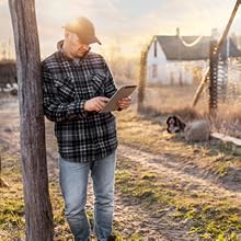 farmer outside leaning on a tree connecting to wifi and internet outdoors