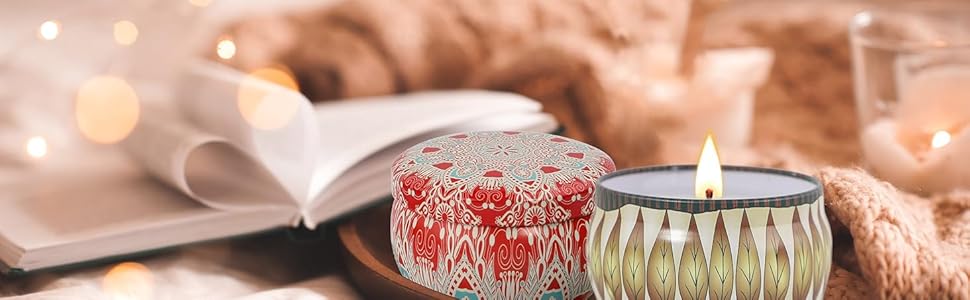 Two decorative candles in glass holders with intricate patterns. One red, one green. Placed on a surface with an open book and warm lighting.