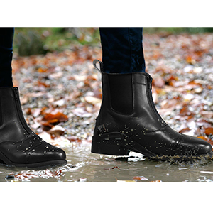 Image of a pair of feet walking through a puddle wearing the paddock boots
