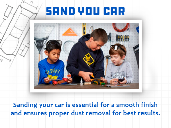 A boy teaching two boys how to sand the wooden car