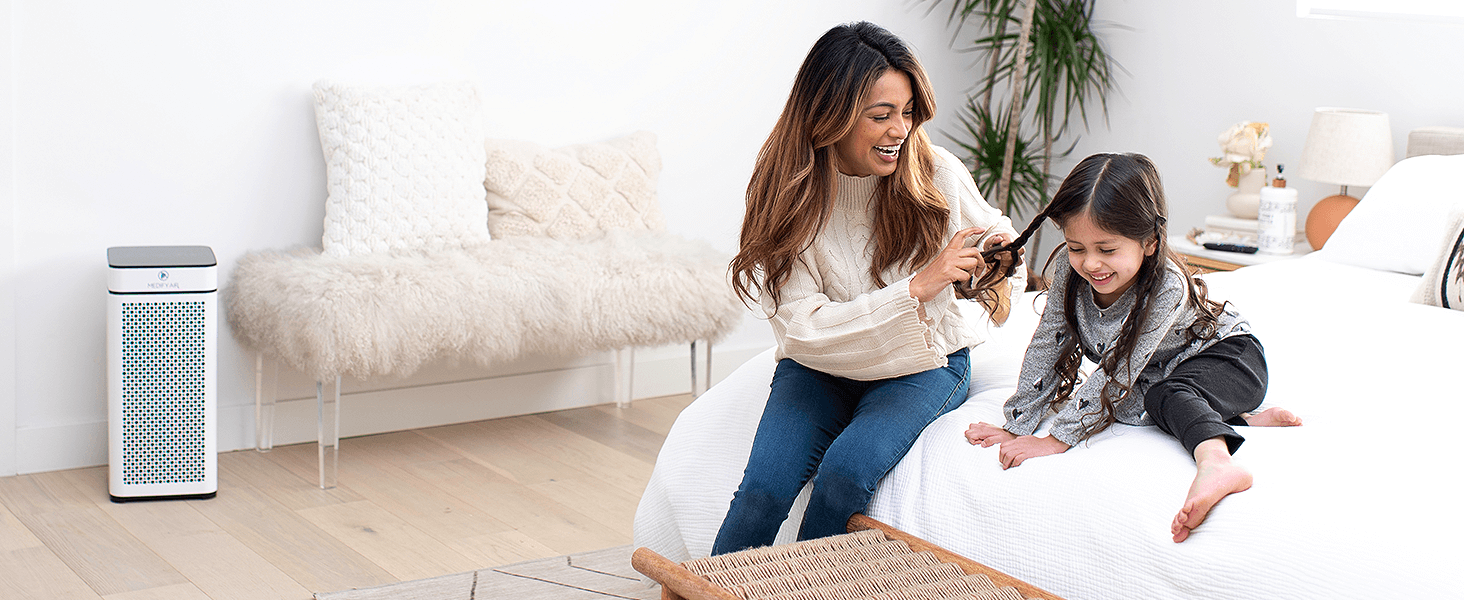 Mother and daughter in a bedroom next to a white MA-40 air purifier