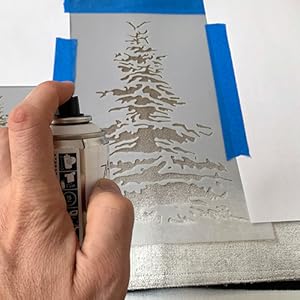 Spray painting a Christmas Tree stencil