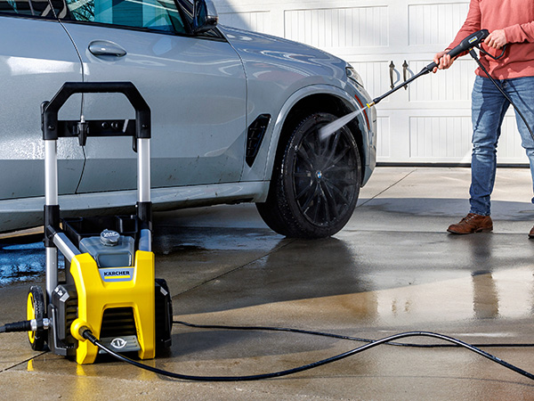A person cleaning a car using a pressure washer