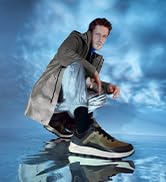 Figura atlética saltando o saltando mientras usa zapatillas contra un espectacular fondo de cielo azul.