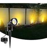 El foco de jardín exterior ilumina una cerca con una iluminación amarilla cálida, creando un ambiente de jardín por la noche.