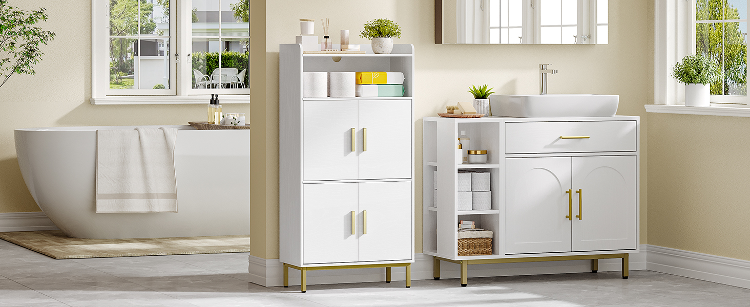 Modernes weißes Badmöbelset mit freistehender Badewanne, Waschtisch mit Waschbecken und Aufbewahrungsschrank. Goldfarbene Hardware-Akzente. Helles, luftiges Zimmer mit Fenstern und Pflanzen