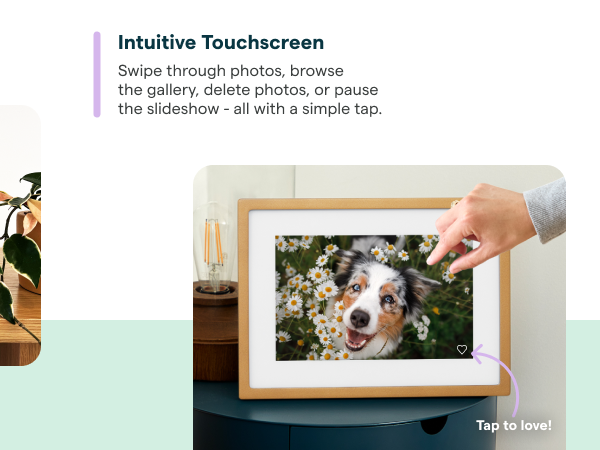 Skylight digital photo frame on table, with hand holding phone.