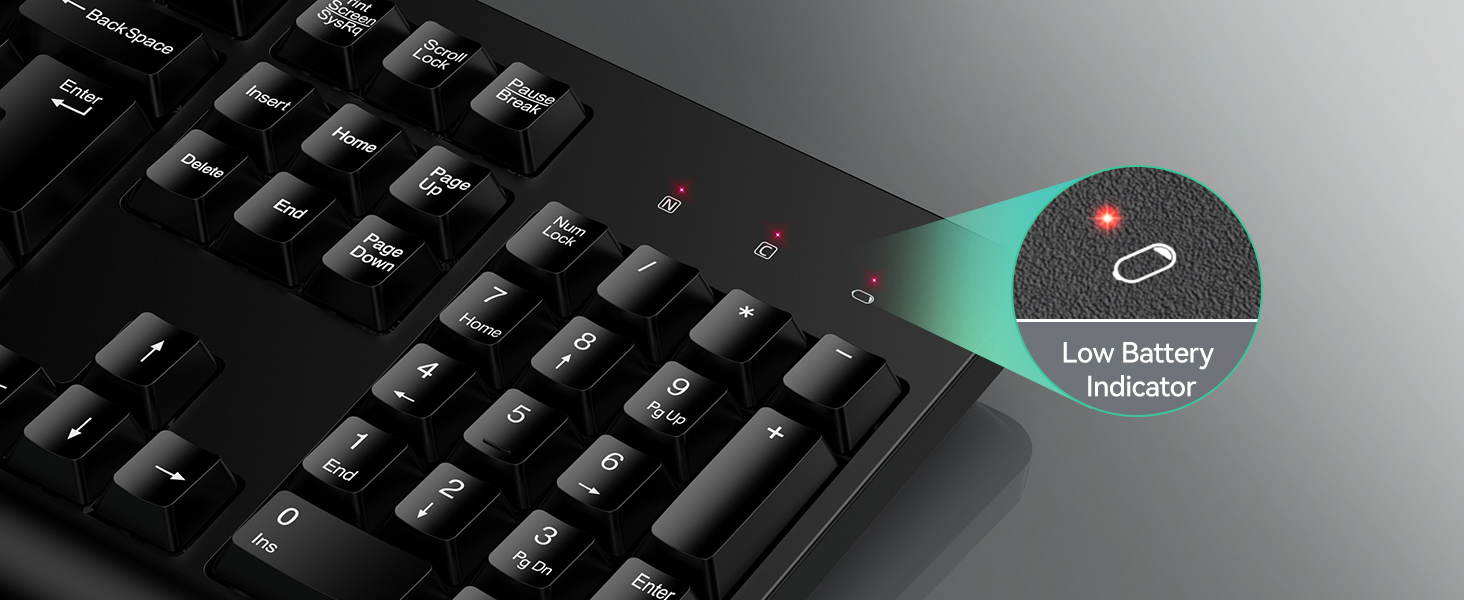 Close-up of keyboard corner with illuminated low battery indicator. Green light visible on a specific key, indicating battery status.