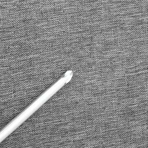 Stylet blanc ou stylo numérique posé sur une surface texturée grise, probablement un tissu ou un tapis