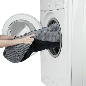 Eine Person nimmt ein Handtuch aus einer Waschmaschine.