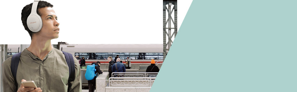 guy in a busy train station, wearing zen hybrid headphones with ambient mode turned on, listening