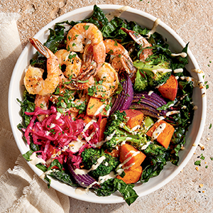 Shrimp over a salad with pickled onions and sweet potatoes
