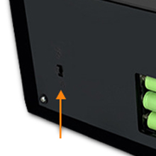 Primer plano de una esquina negra de un dispositivo electrónico, que muestra una flecha naranja que apunta a un puerto numerado e iconos circulares verdes