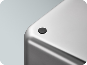 Nahaufnahme einer eleganten silbernen Geräteecke aus Metall mit einem kleinen schwarzen kreisförmigen Taster oder einem Sensor. Die Oberfläche wirkt glatt und hat eine matte Oberfläche.