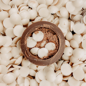half of a hot cocoa bomb, revealing white chocolate chips and cocoa powder