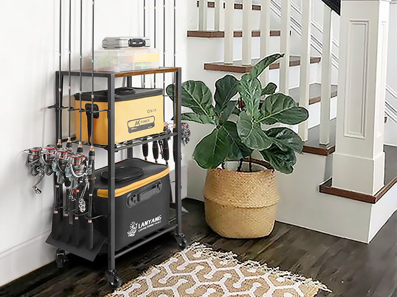 Rolling utility cart with yellow storage bin and hanging tools, placed next to stairs and potted plant. Features multiple shelves and a black metal frame.