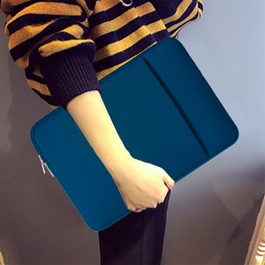 Person holding a navy blue laptop sleeve or case. Sleeve has a slim design with a textured surface.