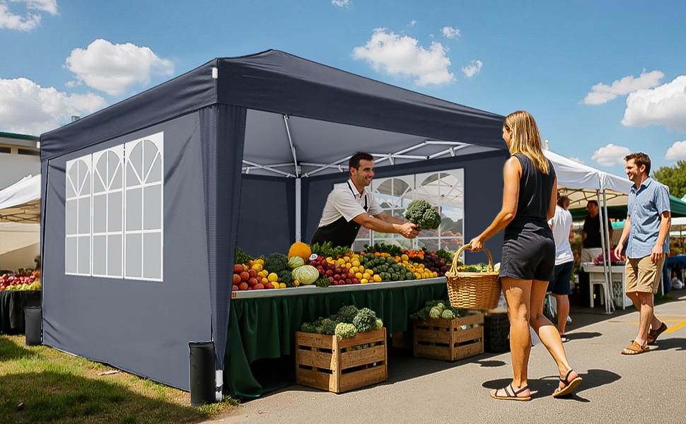 Gray outdoor pop-up canopy tent with window panels, set up at a market stall displaying fresh produce in wooden crates on tables.