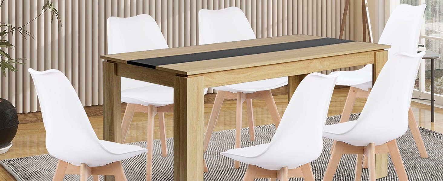 Moderne Essgruppe mit Holztisch mit schwarzem Mittelstreifen, sechs weißen Plastikstühlen mit Holzbeinen, platziert auf einem geometrischen Teppich in einem hellen Raum mit Küstenkunstwerken.