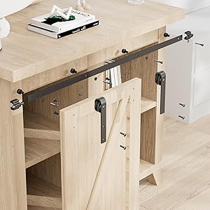 Rustic wooden table with sliding barn door-style cabinet underneath. Metal rail and rollers visible. Books on tabletop.
