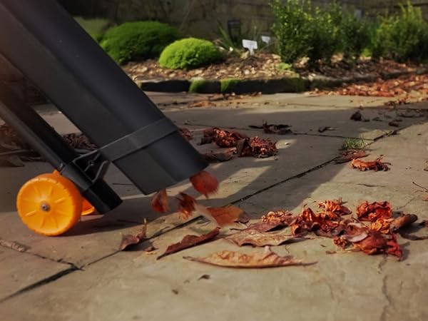 Close-up of chef's knife being used on wooden cutting board with scattered red peppers and vegetables in background.