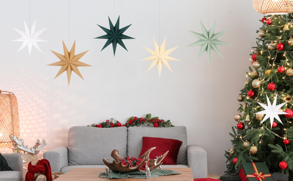 Christmas-decorated living room with a tree, star ornaments on the wall, and a gray couch with red cushion. Bowl of ornaments and reindeer figurine visible.
