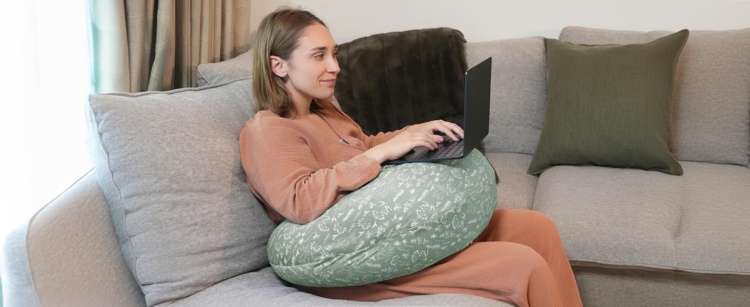 Mint green circular cushion or pillow being used on a gray couch, with olive green decorative pillows in the background.