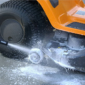 Lawn mower being cleaned with a high pressure washer using detergent