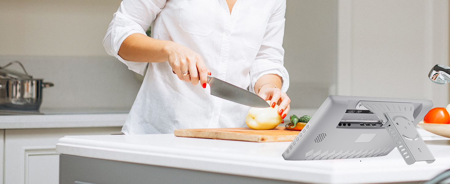 Person im weißen Hemd, die Essen auf einem Schneidebrett in der Küche hackt. Das Tablet-Gerät ist auf der Arbeitsplatte sichtbar und empfiehlt die Verwendung als Rezept- oder Kochanleitung