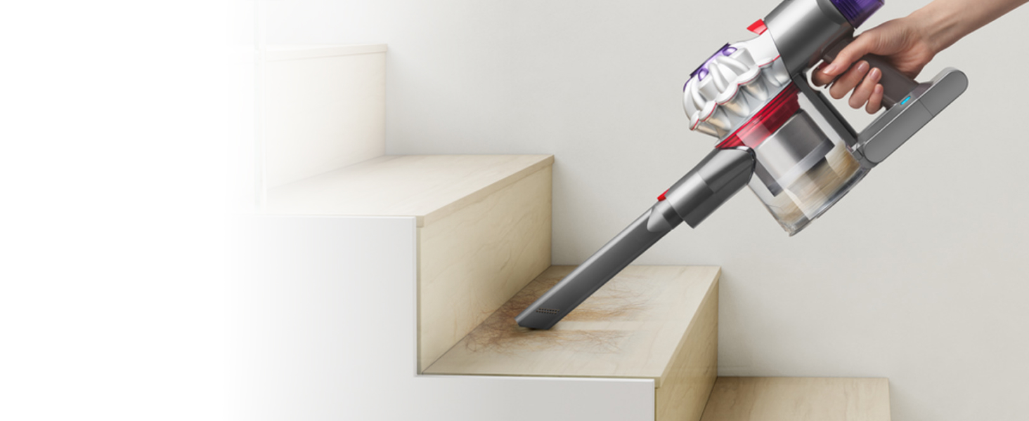 Aspiradora de mano Dyson Car+Boat eliminando la suciedad y el pelo de unas escaleras.
