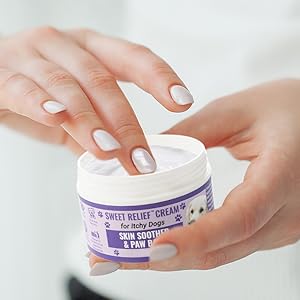 Finger in pot of itch cream for dogs