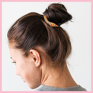 Vue latérale rapprochée d'une cravate en cuir tressé portée dans une coiffure haut de gamme.