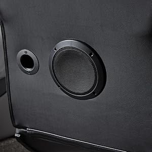 Nahaufnahme eines schwarzen Lautsprechergitters und eines Anschlusses auf einer strukturierten dunklen Oberfläche, die Details der Audioausrüstung zeigt