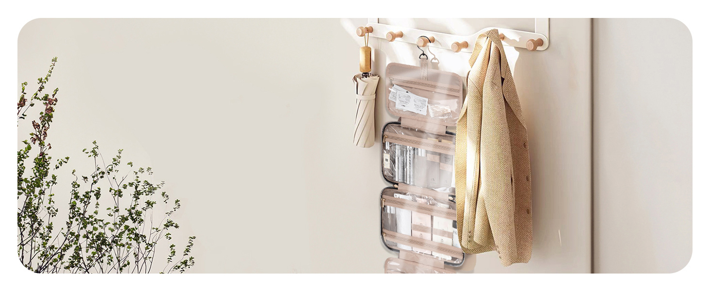 Wall-mounted organizer with clear plastic containers and hooks holding various bathroom items. Beige towel hangs from a hook. Green plant visible in foreground.