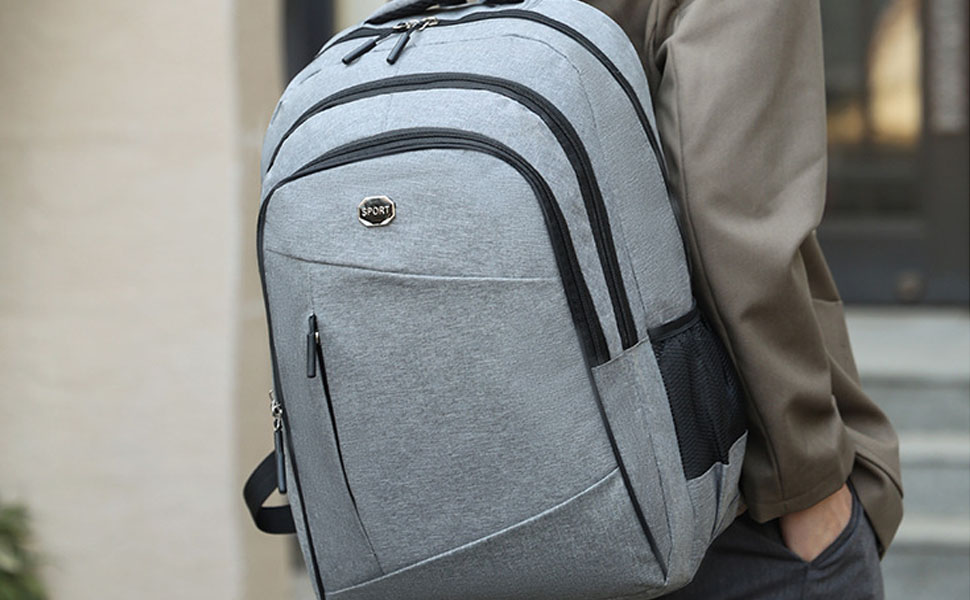 Sac à dos gris clair porté par personne. Dispose de plusieurs compartiments, de bretelles rembourrées et d'un design moderne et élégant adapté à un usage urbain ou professionnel.