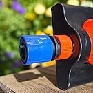 Garden hose nozzle attachment with blue and orange adjustable components mounted on black bracket, photographed against colorful flower background.