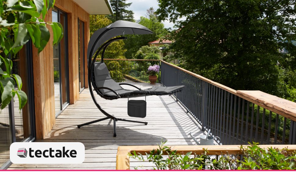 Mobili da giardino per esterni con lettino a baldacchino sospeso. Seduta in rete nera con struttura in metallo curvato e pensilina, posizionata su un ponte in legno con vista sulla foresta