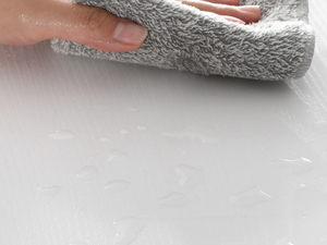 a hand is holding a towel over a white surface.