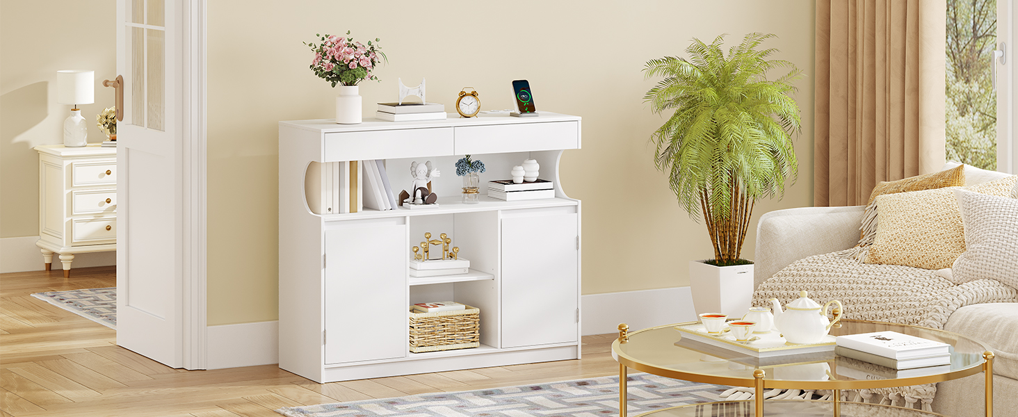 Weißes Sideboard aus Holz mit offenen Regalen und geschlossenen Schränken. Verfügt über eine flache Oberfläche, mehrere Staufächer und steht in einem Wohnzimmer an einer beigen Wand.