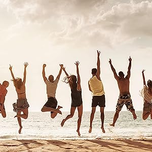 Groep vrienden springen in de lucht met blauwe zee en hemel achtergrond
