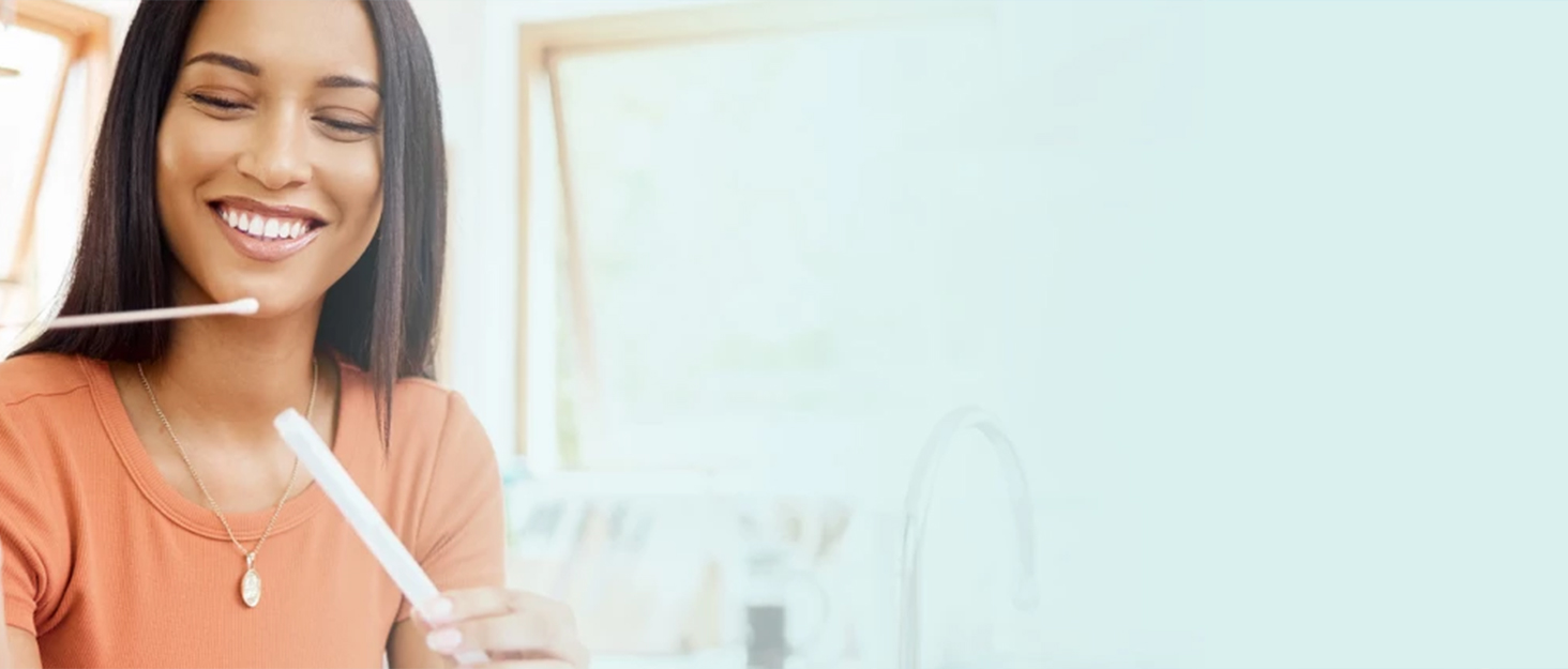 Frau führt mit einem Stäbchen einen Selbsttest durch.
