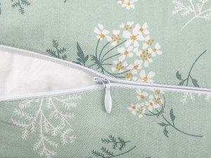 Nahaufnahme eines weißen Reißverschlusses auf einem mintgrünen Stoff mit zartem weißem Blumen- und Farnmuster