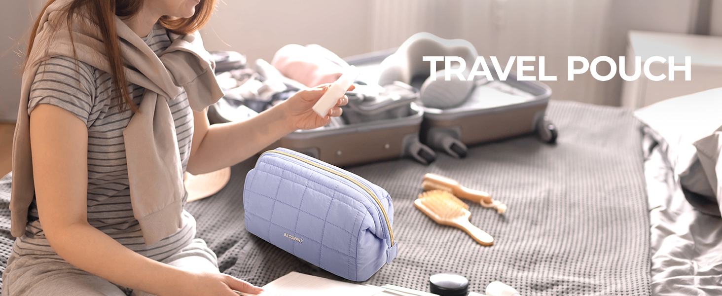 Light purple quilted travel pouch with zipper closure. Shown on bed next to open suitcase, demonstrating its use for organizing travel items.
