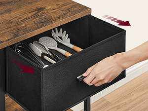 Holztisch mit offener schwarzer Schublade, in der das organisierte Besteck zum Vorschein kommt. Wird von Hand beim Öffnen der Schublade gezeigt, was die einfache Zugänglichkeit demonstriert