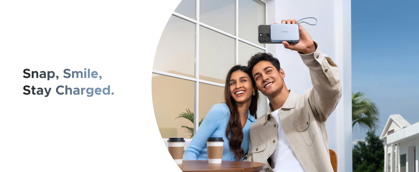 Text reads 'Snap, Smile, Stay Charged.' Two people taking a selfie outdoors with a charging device.