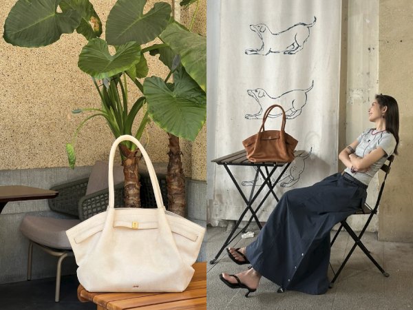 Two canvas tote bags, one white and one brown, displayed near indoor plants and furniture. A curtain with animal prints hangs in the background.