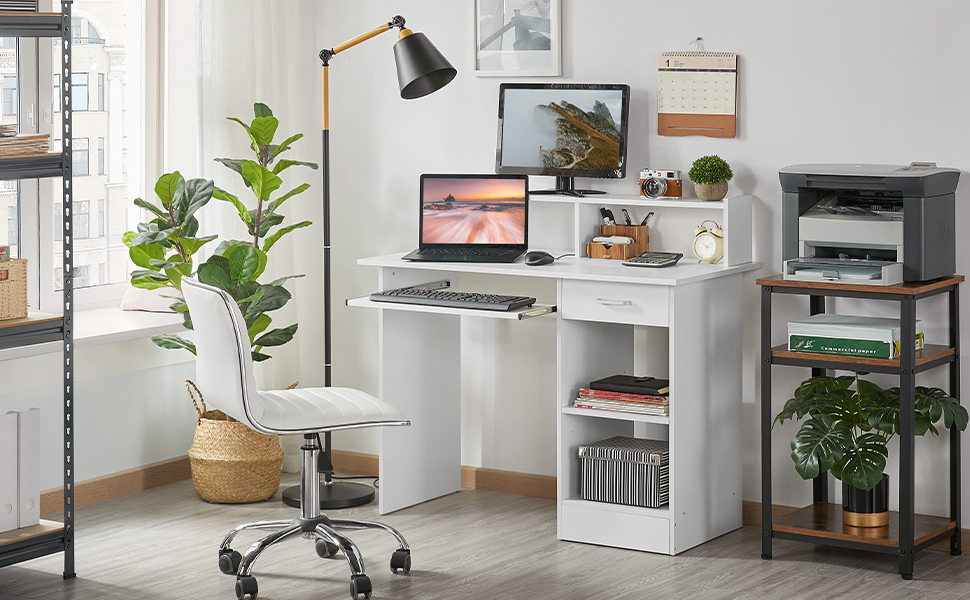 Configuration de bureau à domicile blanche avec ordinateur portable, écran, lampe et étagères de rangement. Comprend une chaise de bureau et des plantes en pot pour un espace de travail complet