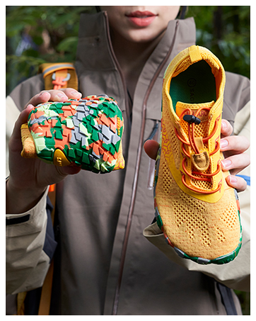 Varias vistas de las manos cogiéndose y mostrando una zapatilla deportiva de malla amarilla y estampada en verde, que muestra diferentes ángulos y detalles.