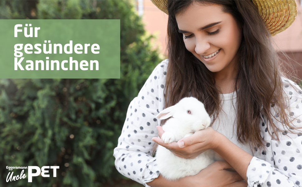 Frau im gepunkteten Hemd hält ein kleines weißes Kaninchen. Texteinblendung auf Deutsch erwähnt gesündere Kaninchen.